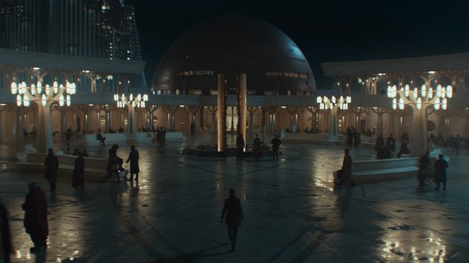 A futuristic plaza at night featuring a large dome structure, illuminated by soft lights and surrounded by people walking along a reflective pavement.